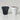 Two small cylindrical planter pots on a light gray studio background, one in matte black and one in matte white, both with visible soil at the top.