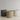 Three minimalist cylindrical planters in matte dark gray, textured beige, and speckled off-white, arranged on a light wood surface against a neutral light gray background.