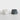 Two modern geometric faceted planter pots on a light gray surface against a white background, one in matte white and the other in dark charcoal gray.
